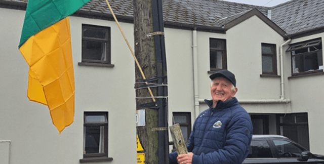 Tom is pictured hanging the flag outside his house ahead of the All-Ireland final