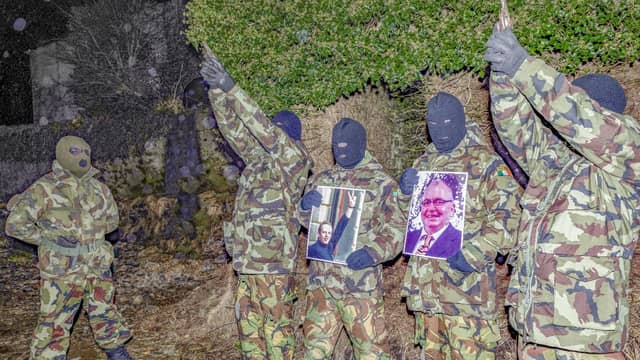 Armed members of the Republican Defence Army holding photos of Pearse McAuley and Don Brolly