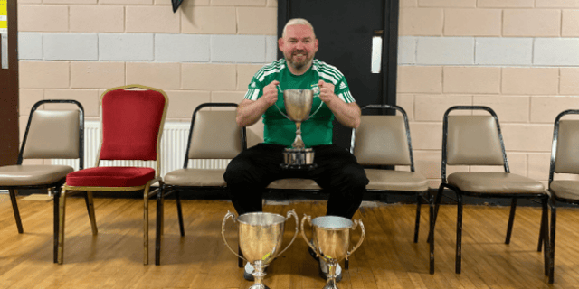 Jason Gibson with the three trophies won by his Bonagee United side.