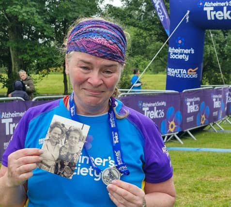 An emotional Geraldine at the finish line with a photo of her mum Margaret, who died in 2025.