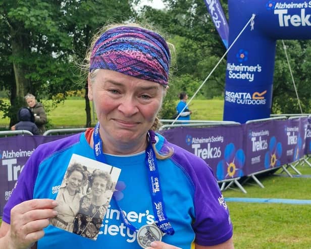 An emotional Geraldine at the finish line with a photo of her mum Margaret, who died in 2025.