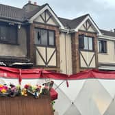 External view of a house showing signs of fire damage, with a forensic tent erected outside
