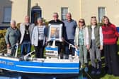 Moville Tidy Towns committee members present Fr Colm O’Doherty with a framed picture of Moville Lighthouse in recognition of his success in the Large Garden category of the competition.