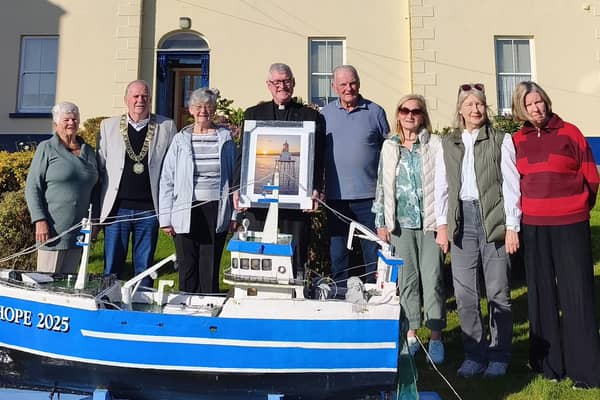 Moville Tidy Towns committee members present Fr Colm O’Doherty with a framed picture of Moville Lighthouse in recognition of his success in the Large Garden category of the competition.